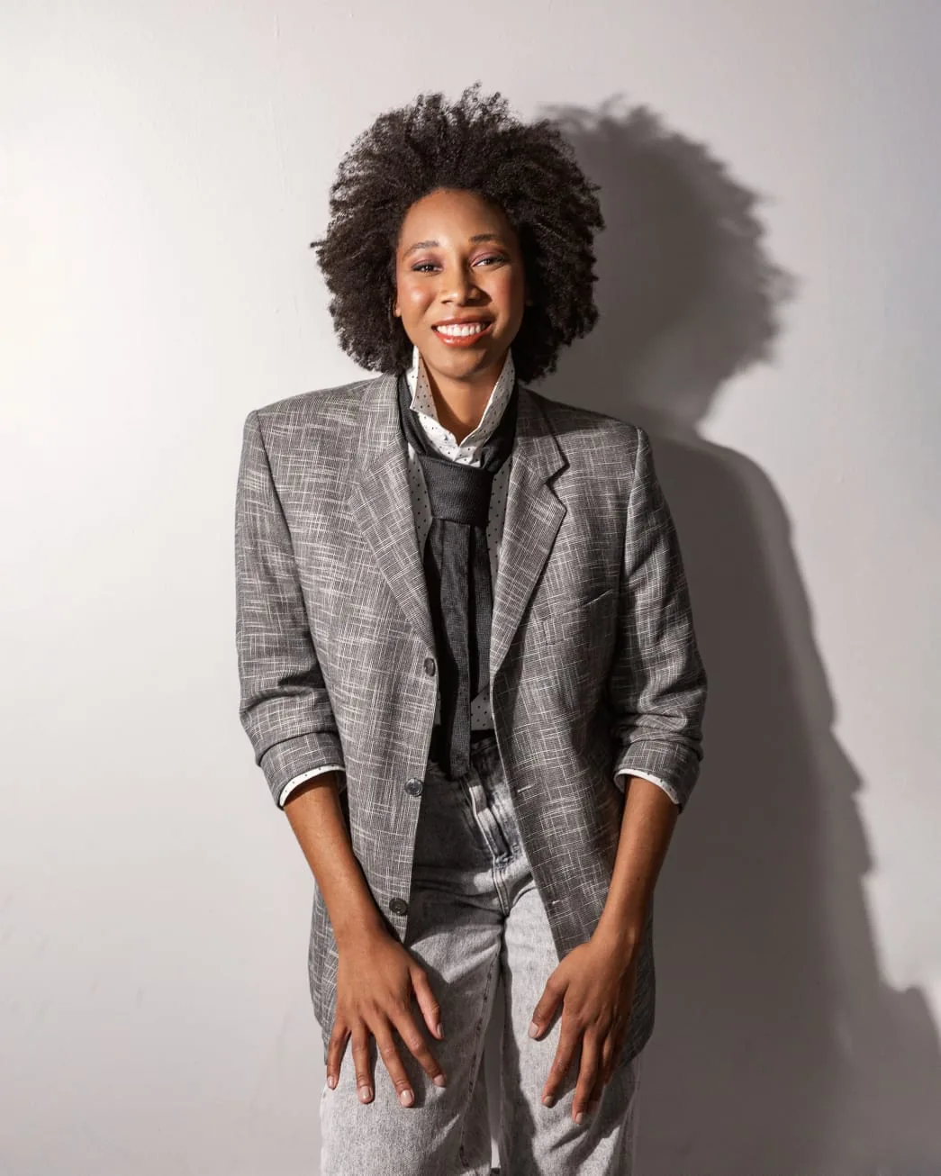 Editorial — blazer cinza em pé, sorrindo